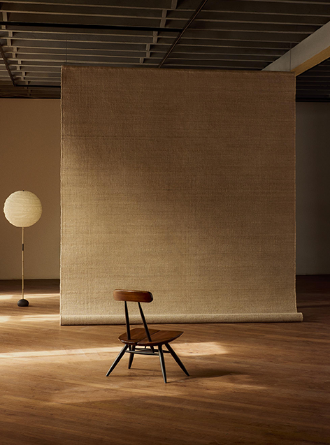 Interior scene with a chair in front of a hanging textile