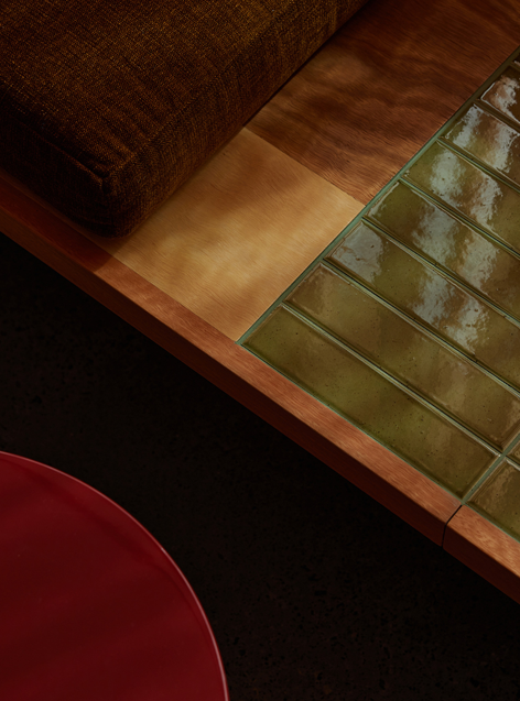 Interior arrangement with a sculptural pedestal, wooden stool, and circular wall piece